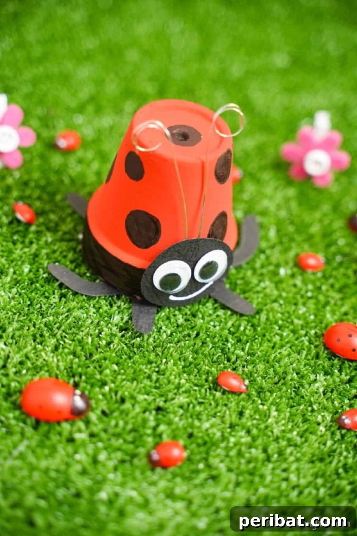Adorable Upcycled Ladybug Planter Craft 16 The finished ladybug flower pot proudly displayed on green grass, accompanied by small decorative ladybug rocks.