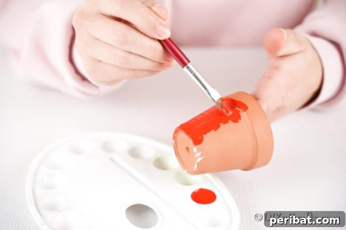 Adorable Upcycled Ladybug Planter Craft 8 A terra cotta flower pot being painted a bright red, marking the first step in creating the ladybug.