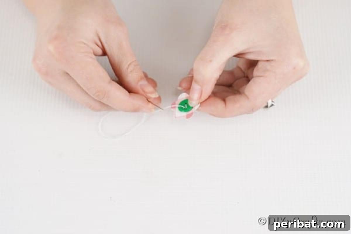 DIY Paper Button Blossoms 9 Hand sewing a button onto a paper flower for added detail