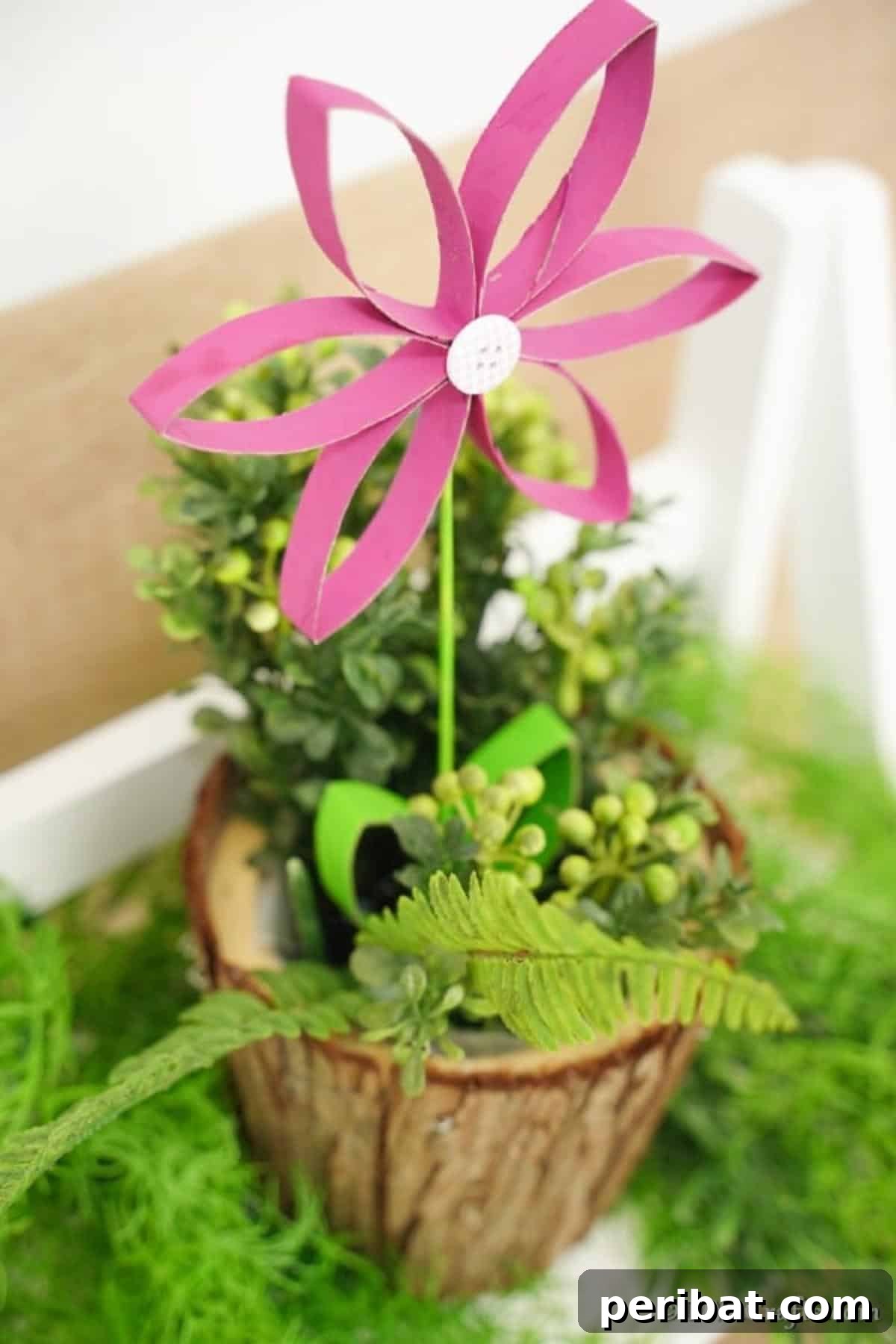 Pink paper roll flower sitting inside a wooden planter