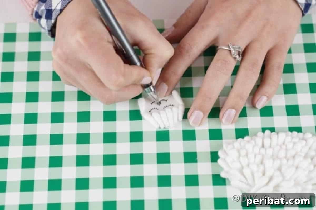 Drawing a cute face with a black marker on the small circle and adding cotton swab pieces around the edges for a fluffy head.