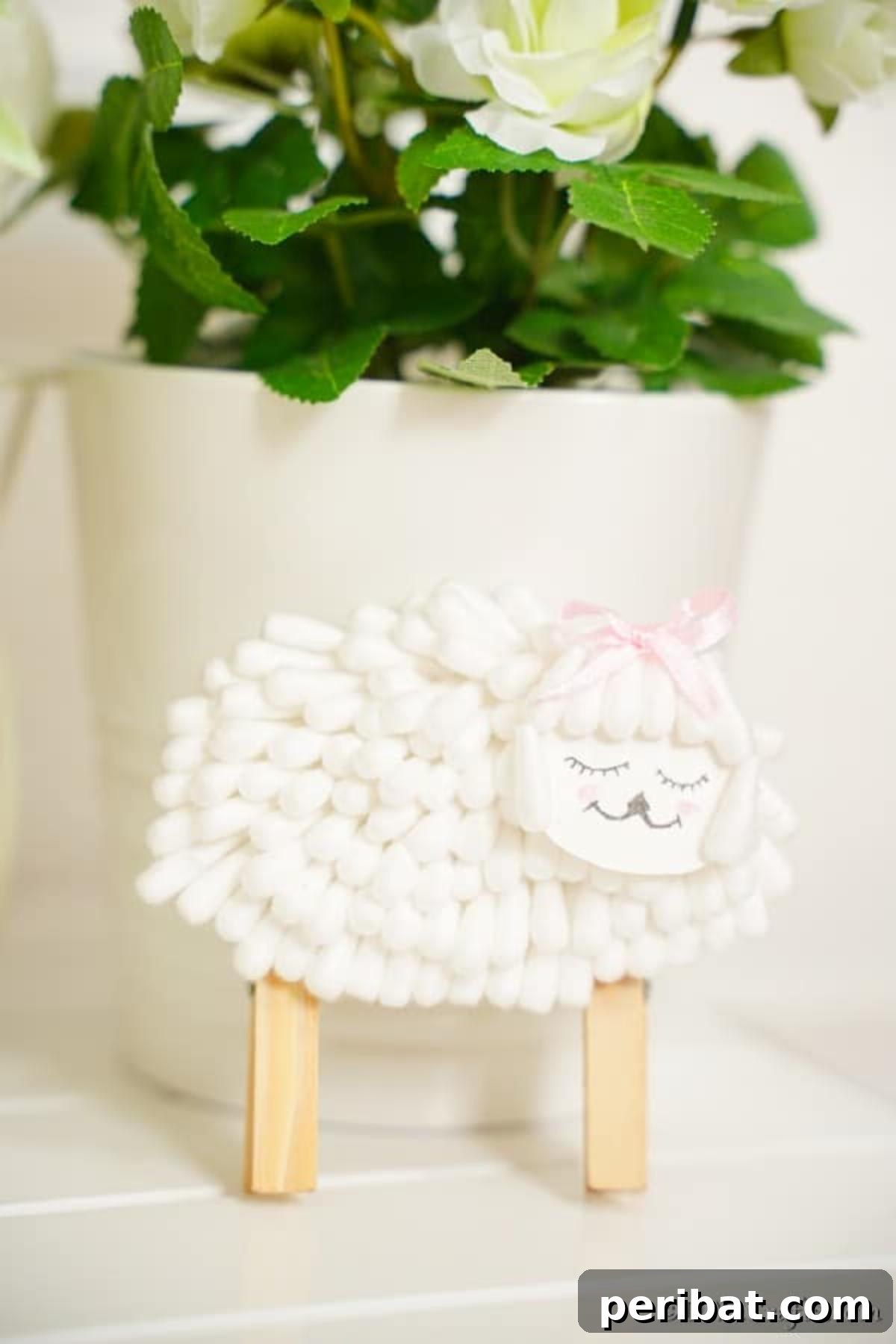 Finished cotton swab lamb standing proudly, leaned against a white flower pot, showcasing its completed form and readiness for display.