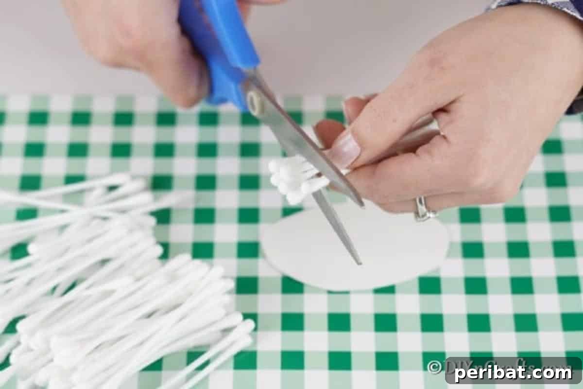 Carefully cutting cotton swabs in half to prepare the lamb's fluffy texture, a crucial step for the craft.
