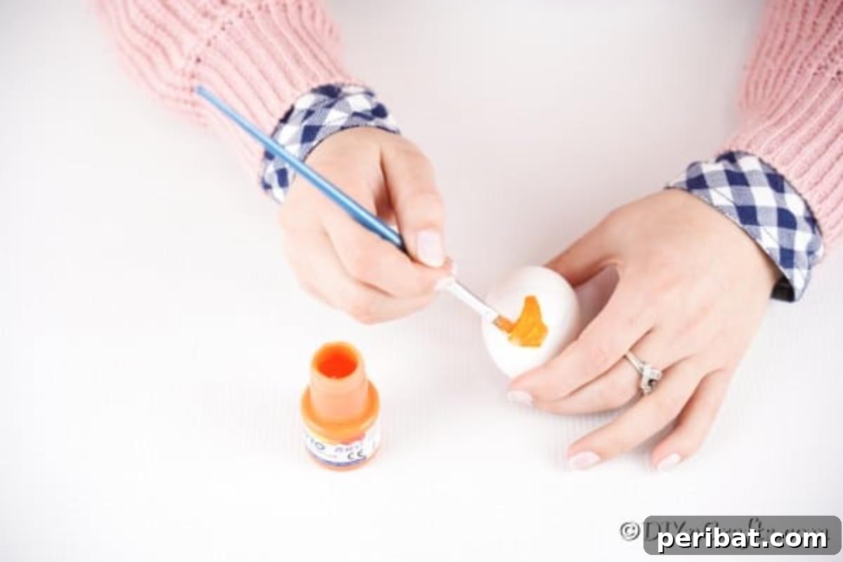 Foxy Fun DIY Easter Egg Project 10 Step-by-step image showing the egg being painted orange, leaving the stomach and eye areas unpainted.