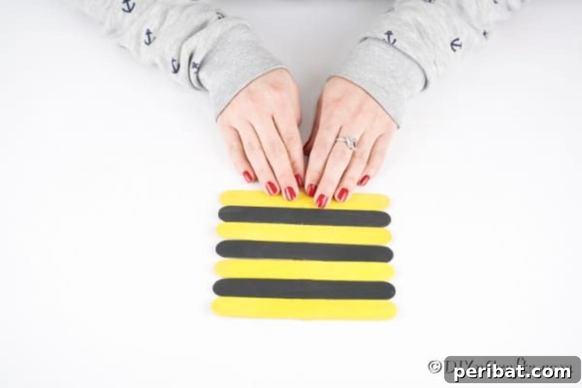 All the black and yellow craft sticks glued together in an alternating pattern, forming the striped body of the bee.