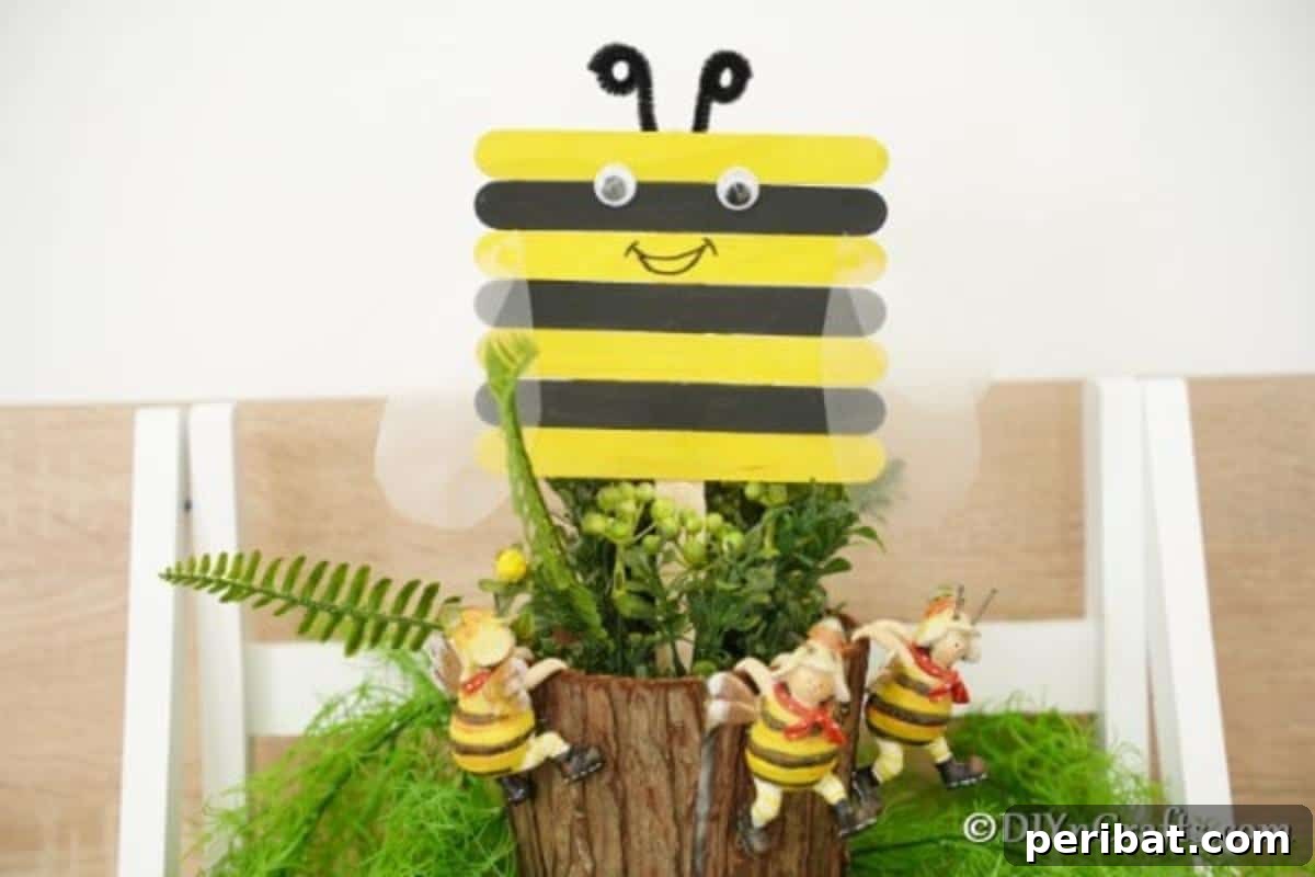 A finished craft stick bee happily displayed in a potted plant, ready to brighten up any space.