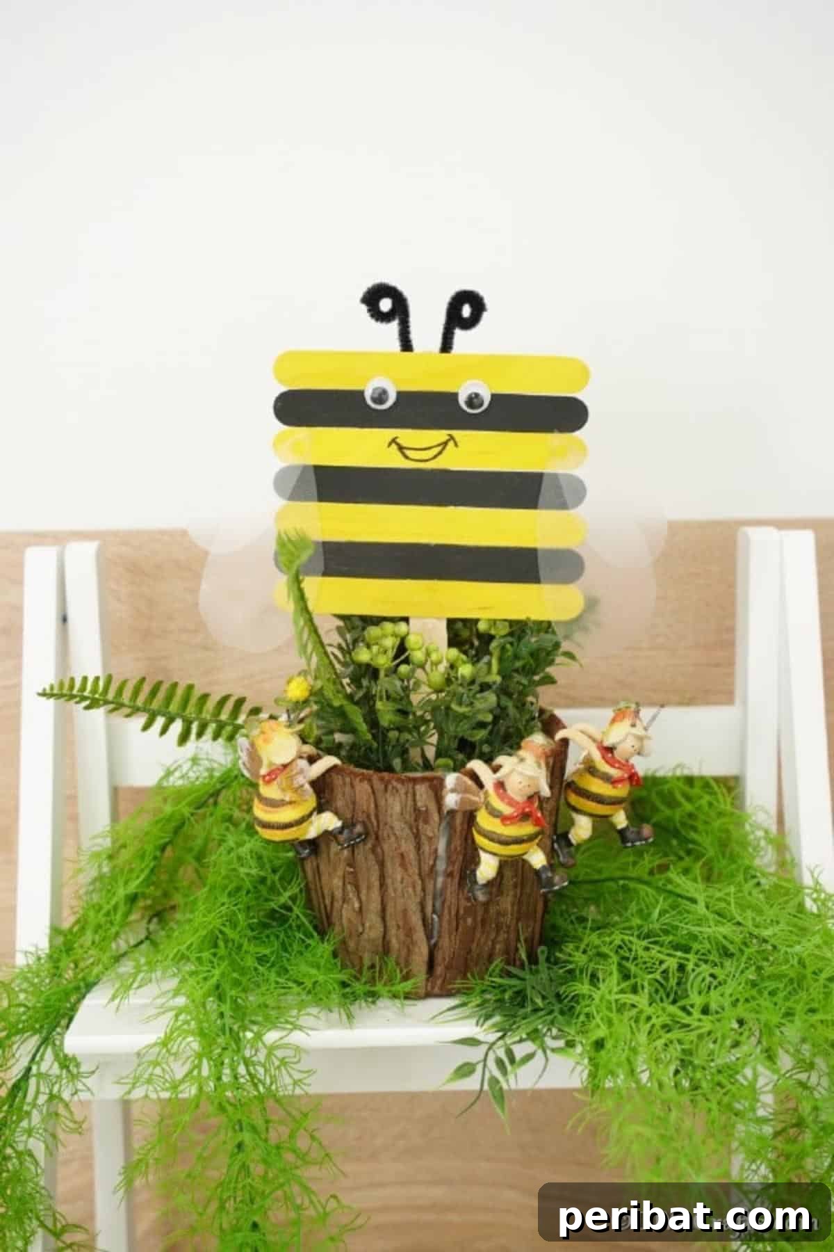 A handmade craft stick bee carefully placed in a green potted plant, adding a touch of whimsy to the decor.
