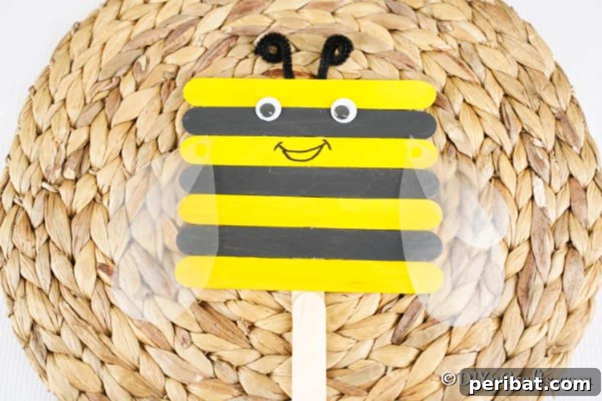 A close-up shot of a finished craft stick bee resting on a woven mat, showcasing its intricate details and cheerful expression.