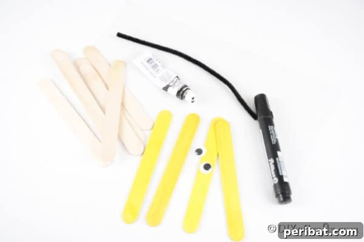A flat lay of all the essential supplies needed to create the craft stick bee, including paints, sticks, googly eyes, and glue.