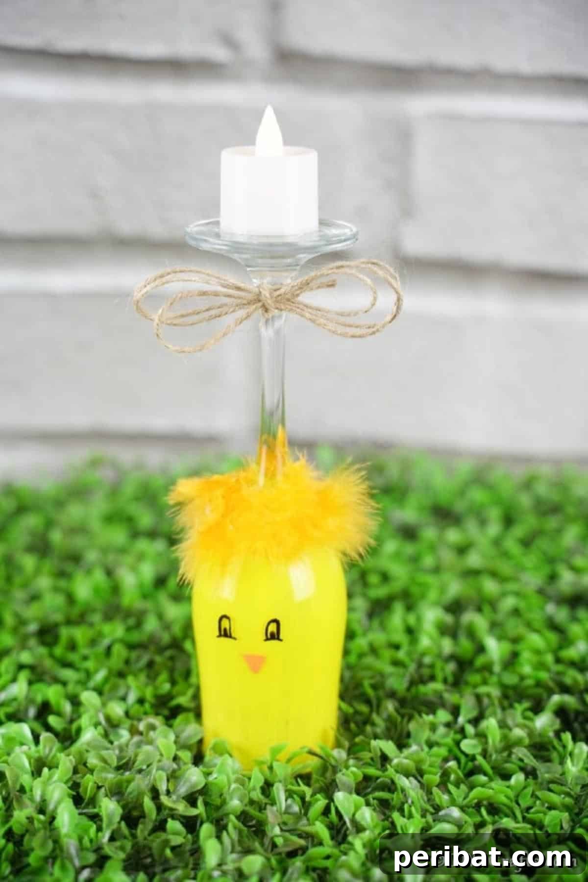 Adorable DIY Chick Wine Glass Luminary 5 A vibrantly yellow painted wine glass chicken sits on fake grass, adding a playful touch to outdoor Easter decorations.