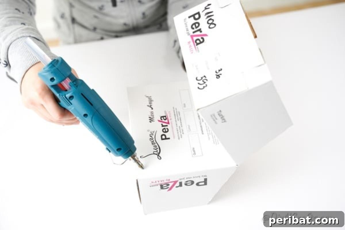 Charming Repurposed Cardboard Organizer 13 Applying hot glue to securely join the folded box sides, creating dual and stable pockets