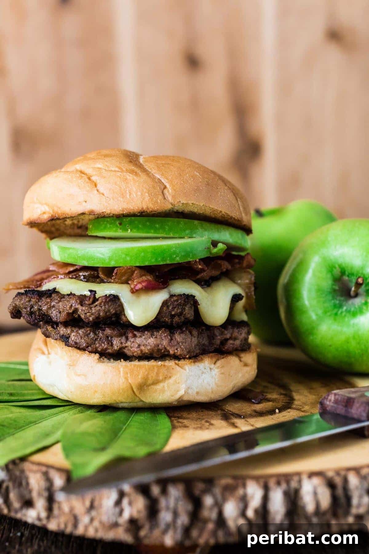 Bacon Beyond Belief: 26 Recipes for an Unforgettable Feast 23 A gourmet burger featuring a juicy beef patty topped with crisp apple slices, smoky bacon, and creamy melted brie cheese.