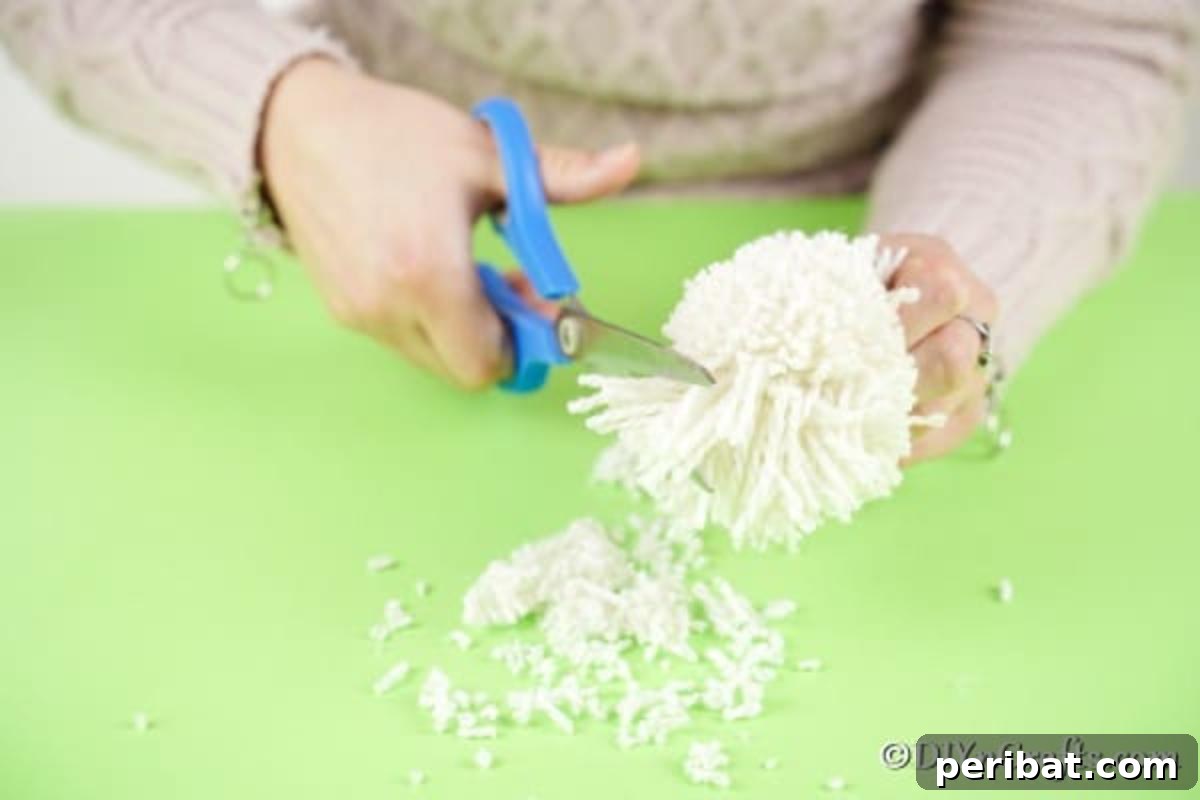 Fluffy Pom-Pom Sheep: A DIY Video Craft Guide 11 Hands carefully trimming the edges of a partially fluffed yarn pom pom with scissors, aiming to achieve a perfectly rounded and even shape.