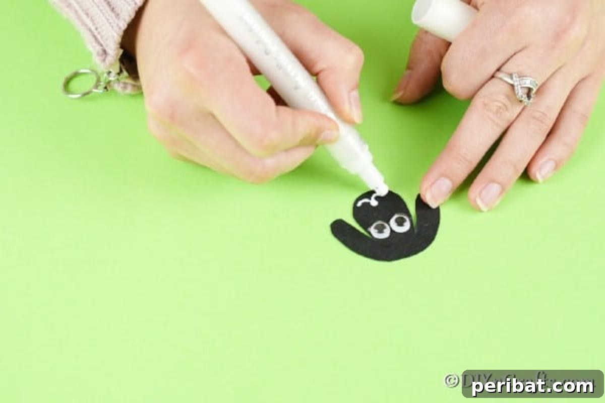 Fluffy Pom-Pom Sheep: A DIY Video Craft Guide 13 A close-up of a black paper sheep face with googly eyes glued on and a happy white smile drawn with a paint pen, demonstrating how to add personality to the craft.