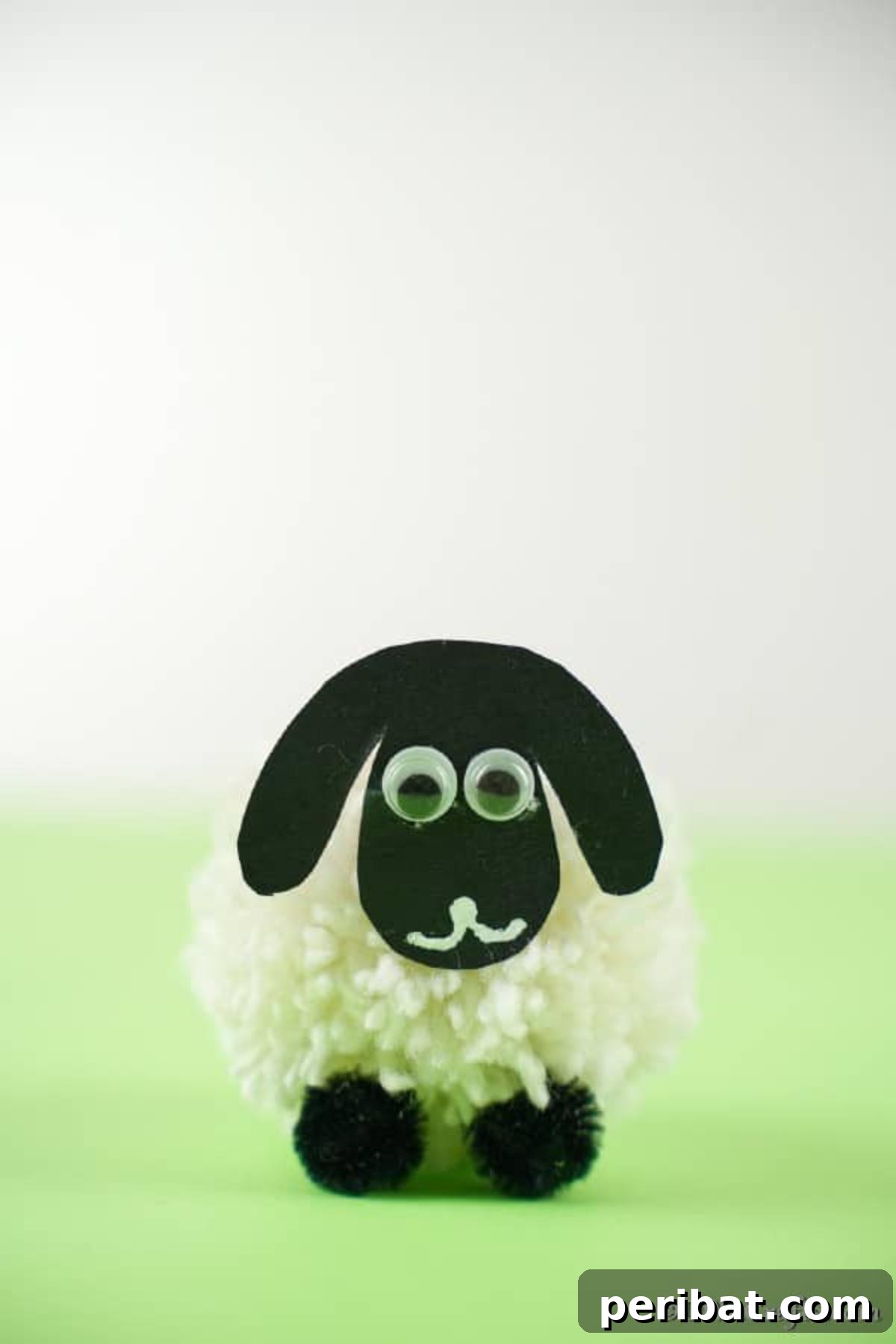 Fluffy Pom-Pom Sheep: A DIY Video Craft Guide 4 A simple yet adorable DIY pom pom sheep craft, positioned on a vibrant green surface with a clean white background, highlighting its handmade charm and fluffy texture.