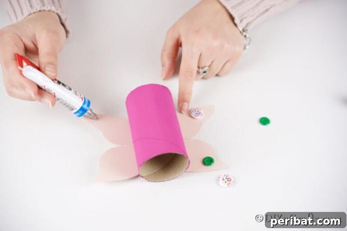 Close-up of buttons being glued to the paper wings of a butterfly craft