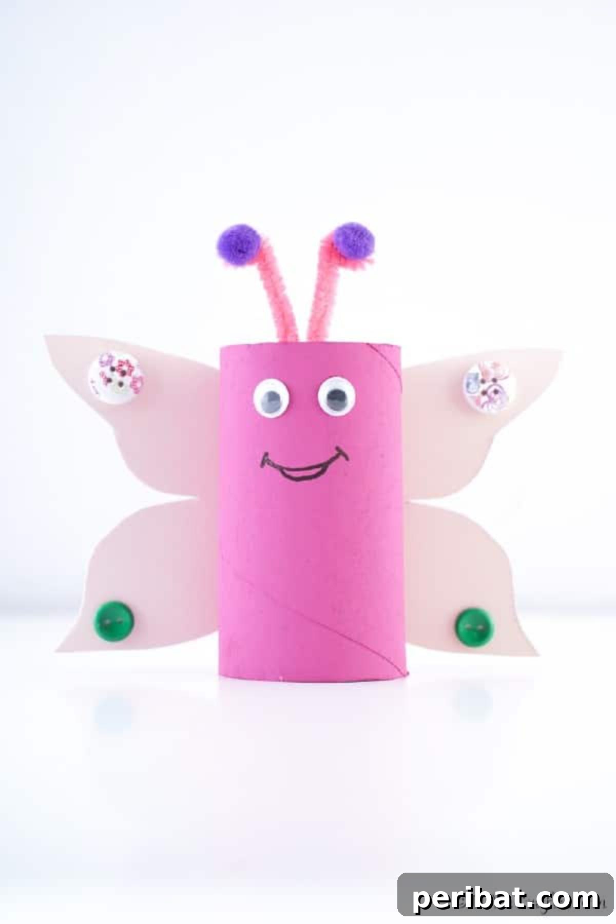 Close-up of a pink paper roll butterfly craft on a white surface