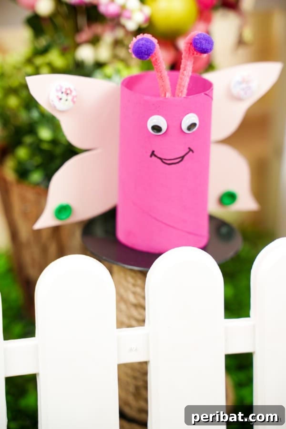 Pink paper roll butterfly on a white fence with blooming flowers
