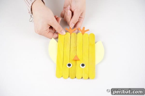 Colorful Craft Stick Chicken Painting 25 Gluing the beak and feet onto the chick.