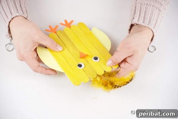 Colorful Craft Stick Chicken Painting 26 Attaching a feather to the chick's head for a fluffy top.