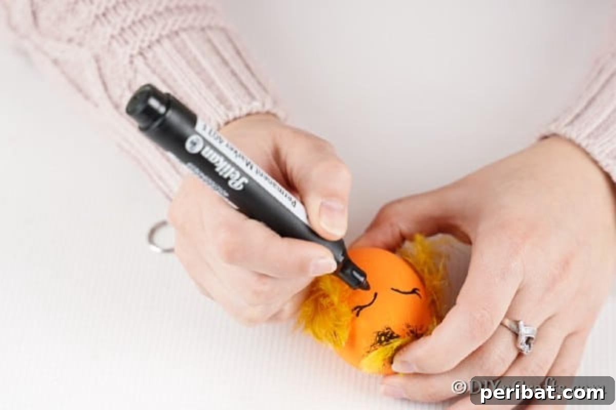 Craft Adorable Easter Egg Chickens A Step by Step Video Guide 11 A hand using a black paint pen to draw small, expressive eyes onto the painted egg