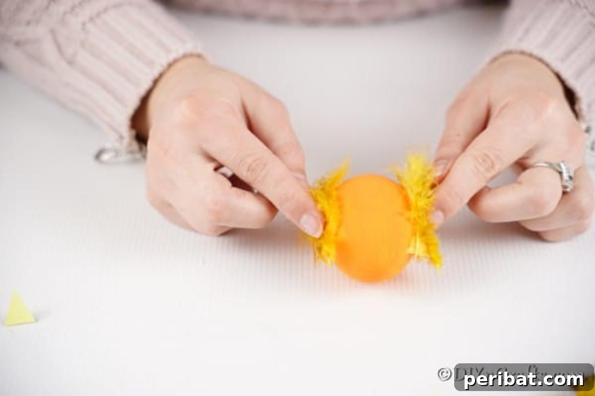 Craft Adorable Easter Egg Chickens A Step by Step Video Guide 10 A close-up view of feathers being glued onto the sides of an egg to create the chicken's wings