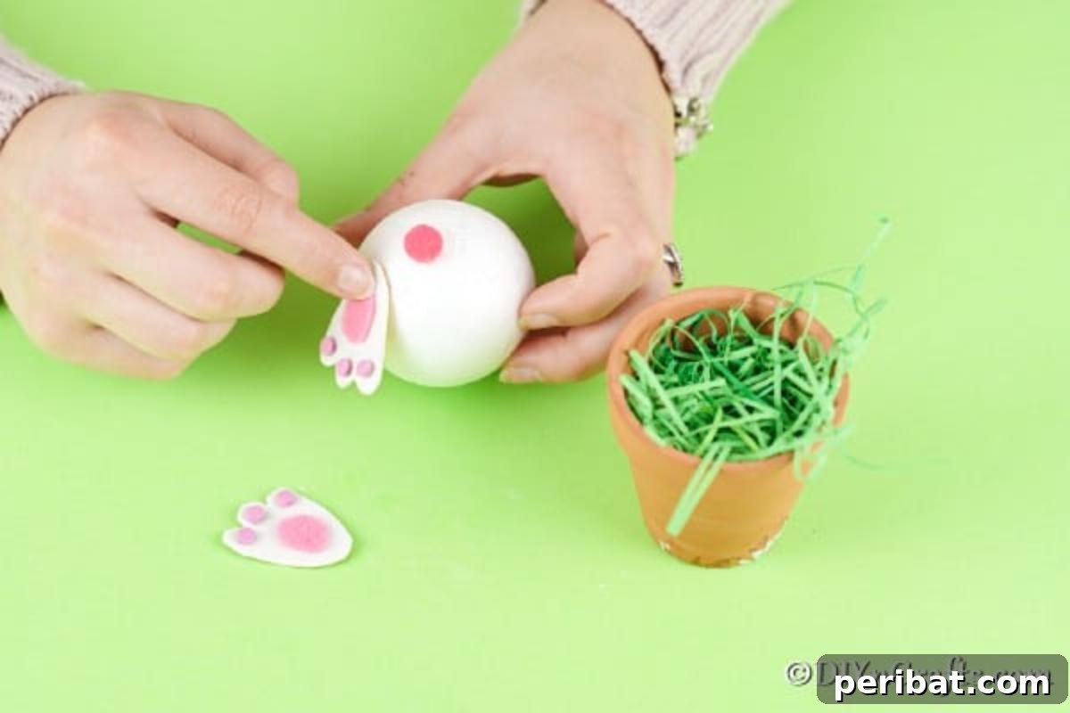 Easter Bunny Bloom Hideaway 11 Attaching the crafted bunny feet to the styrofoam ball, positioning them whimsically near the tail