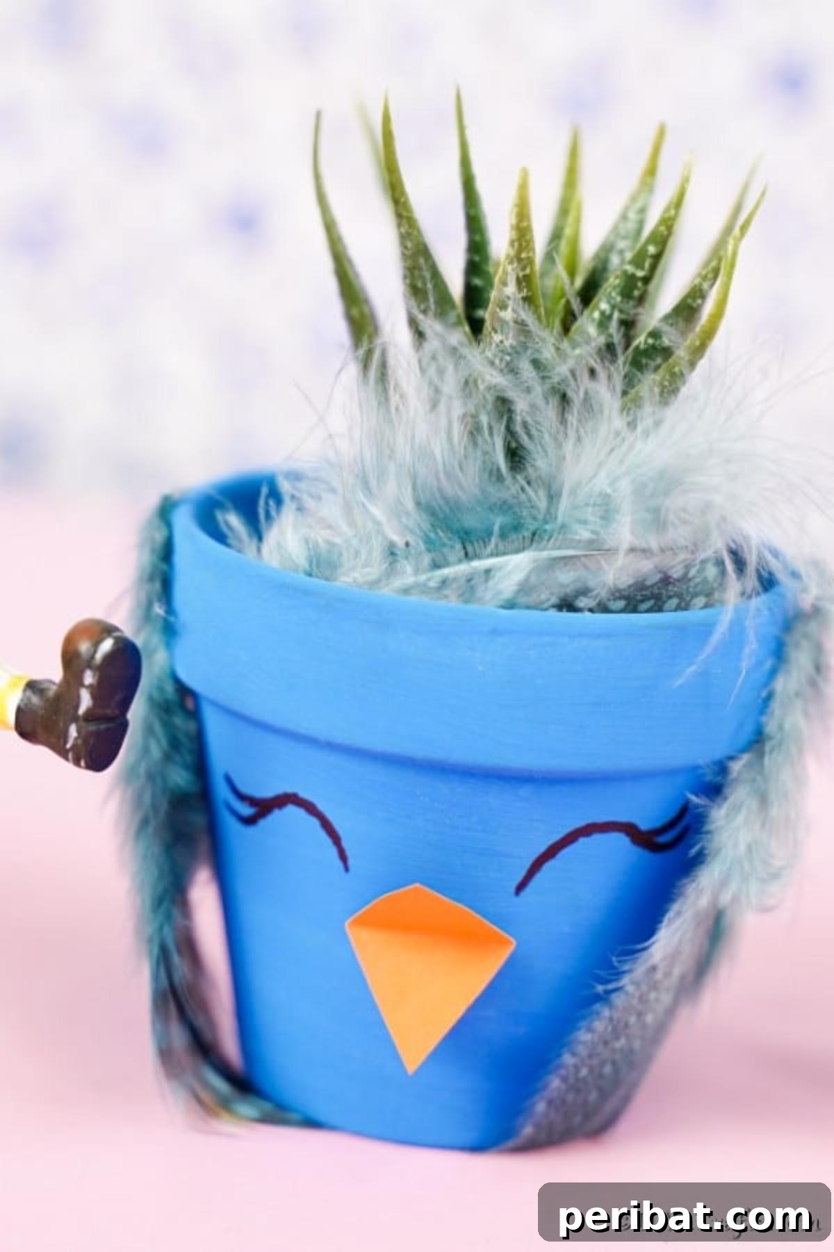 Whimsical Hand-Painted Bird Planter Charm 4 A vibrant blue bird flower pot resting on a soft pink surface