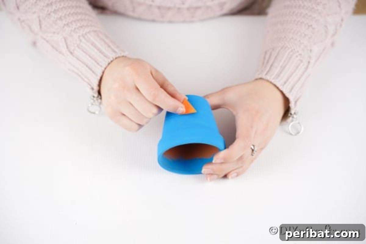 Whimsical Hand-Painted Bird Planter Charm 9 Gluing the folded orange paper beak onto the blue flower pot