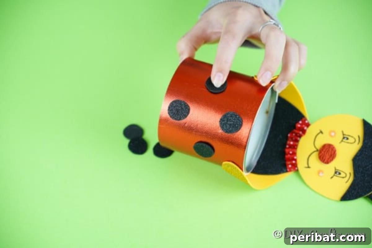 Gluing black dots onto the red ladybug tin can body