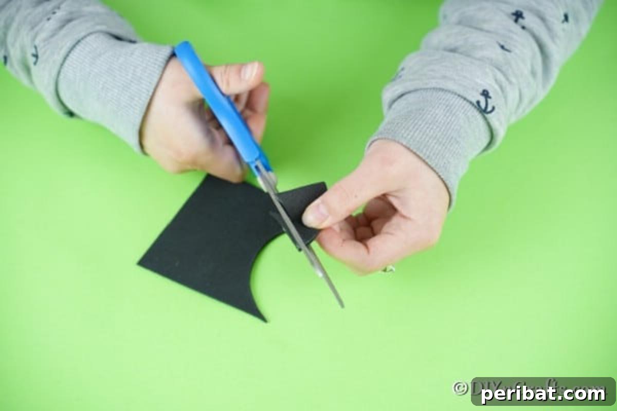Cutting out the black ladybug head with a scalloped edge
