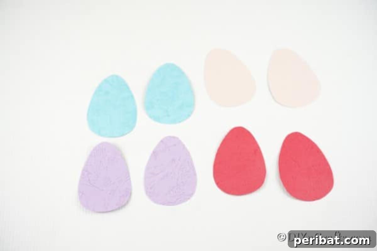 Whimsical Pasta Easter Egg Garland 11 Multiple paper eggs in shades of pink, blue, purple, and red, neatly arranged on a white surface