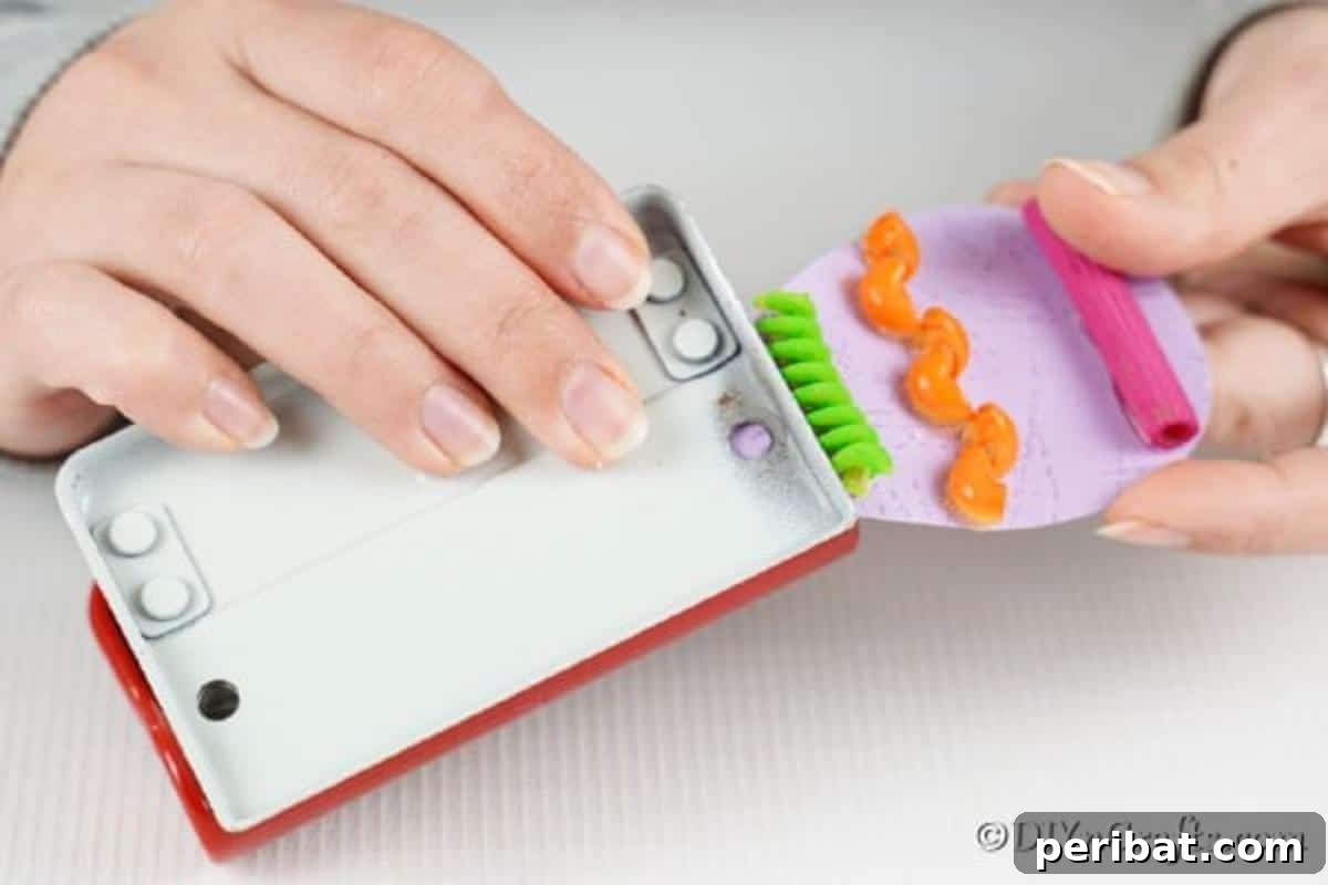 Whimsical Pasta Easter Egg Garland 15 A hand using a hole punch to create a hole at the top of a paper egg for hanging