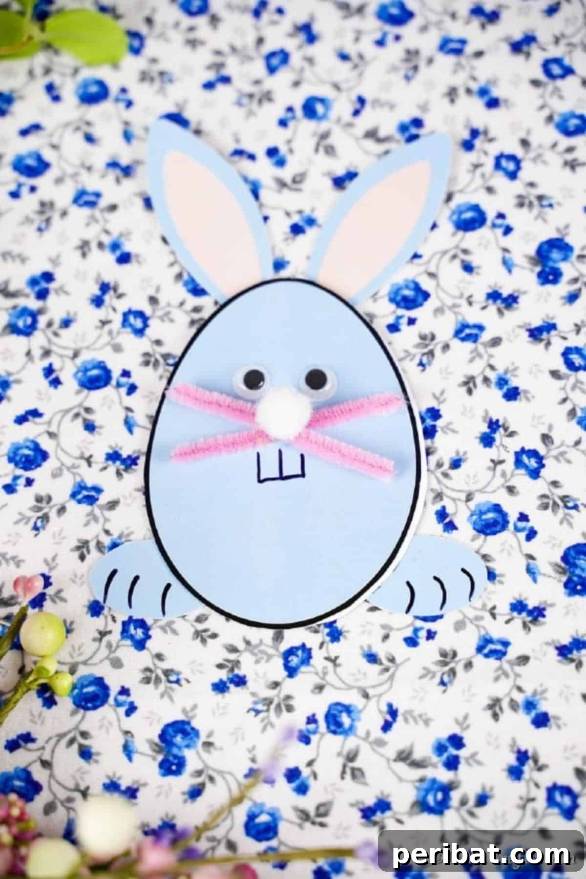 A beautifully decorated egg-shaped Easter bunny card resting on a floral background, ready for display or gifting.