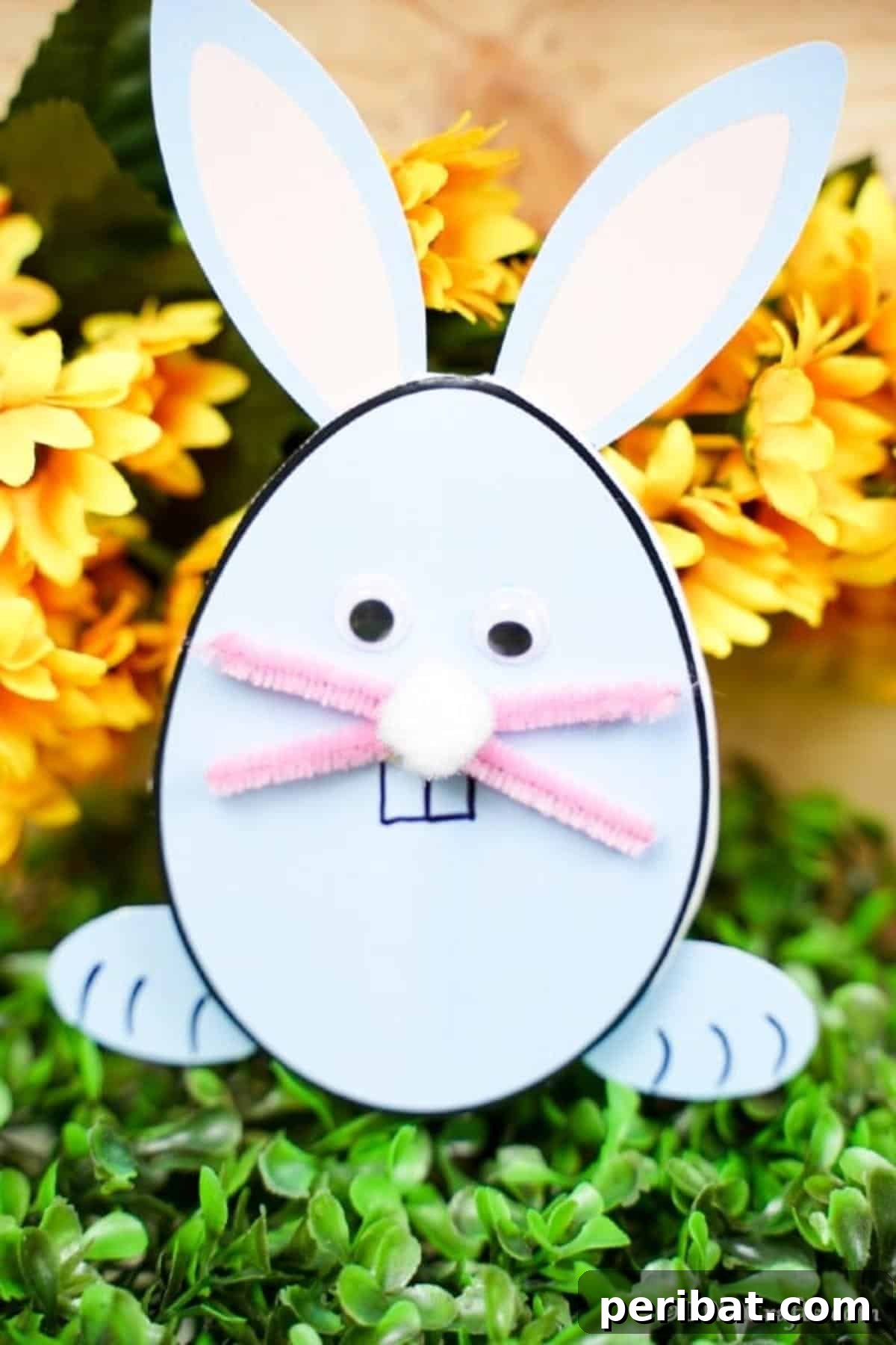 A charming egg-shaped Easter bunny card resting on artificial green grass, surrounded by miniature Easter decor, creating a festive scene.