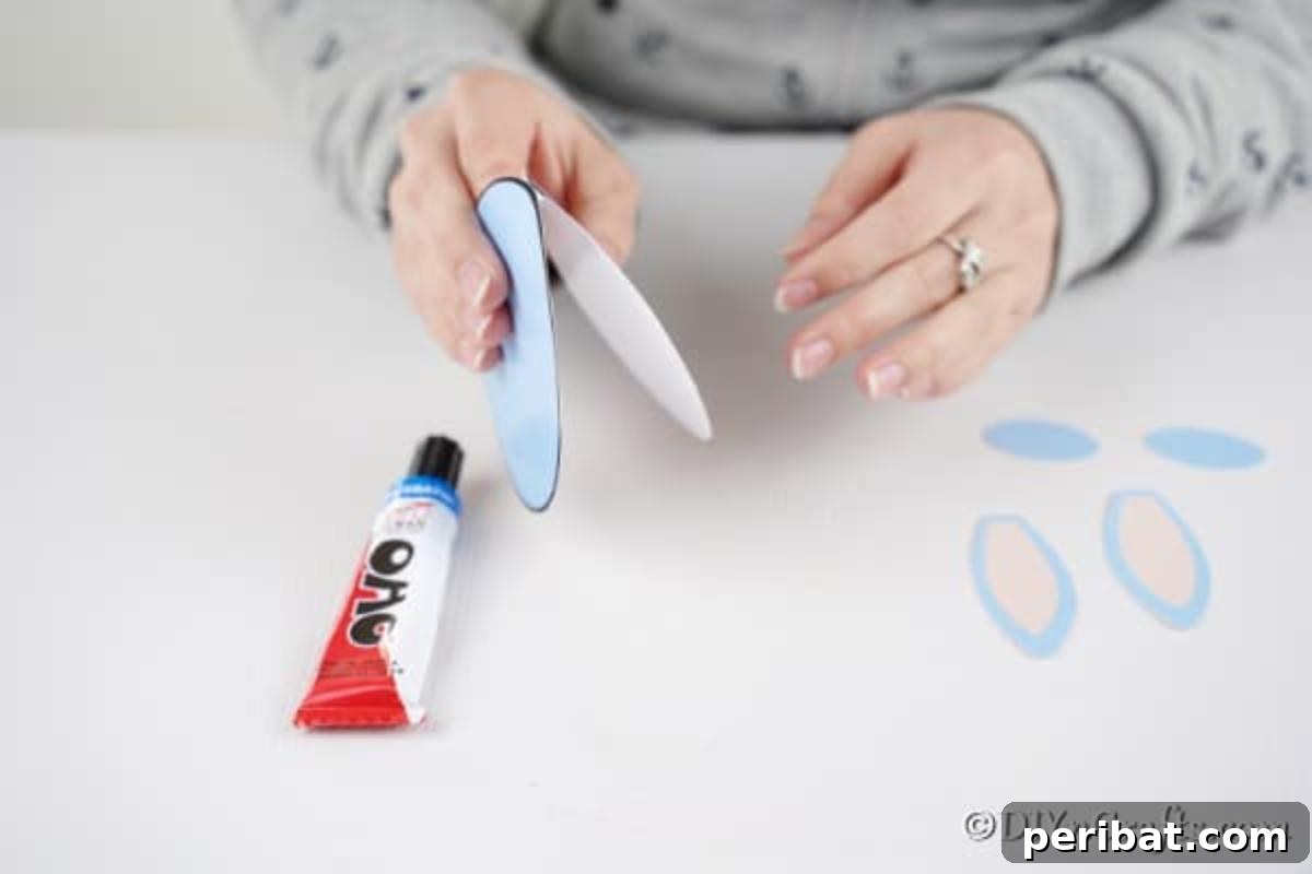 Hands folding the double-sided egg shape in half to create the card base, illustrating the card's structure.