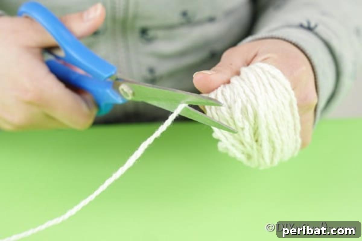 Whimsical Nordic Easter Gnome Creation 8 Hands securing a bundle of white yarn by tying a small piece of yarn tightly around its middle.