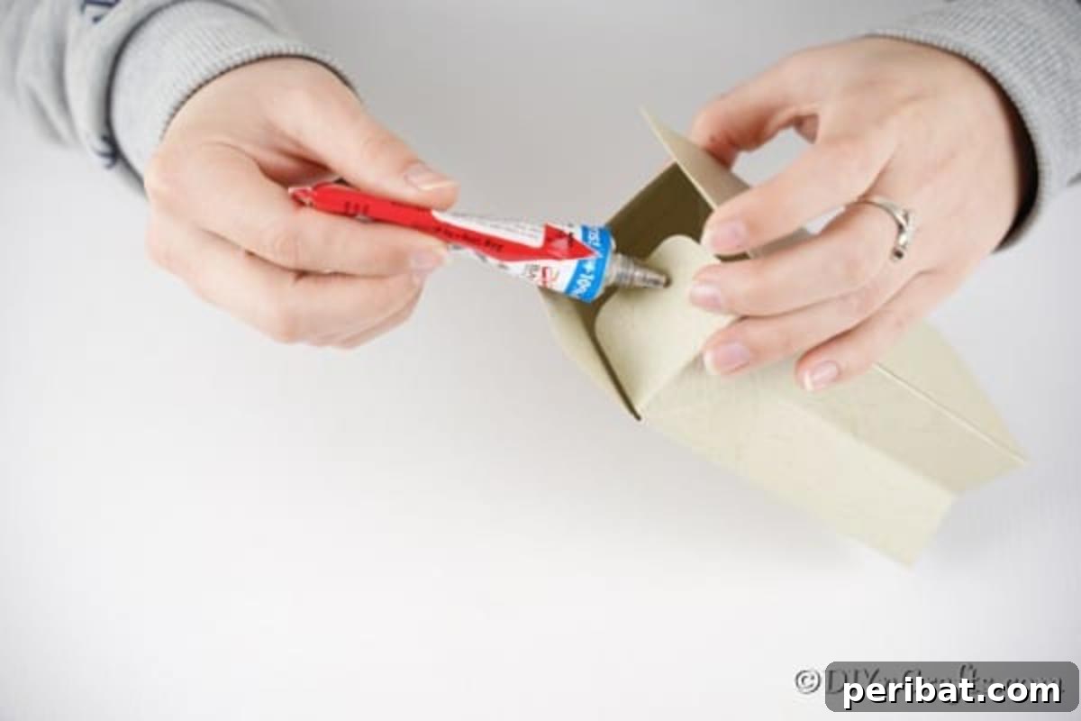 DIY Easter Treat Pouch Video Guide 11 A hand applying glue to the side seam of the folded paper bag to secure its shape