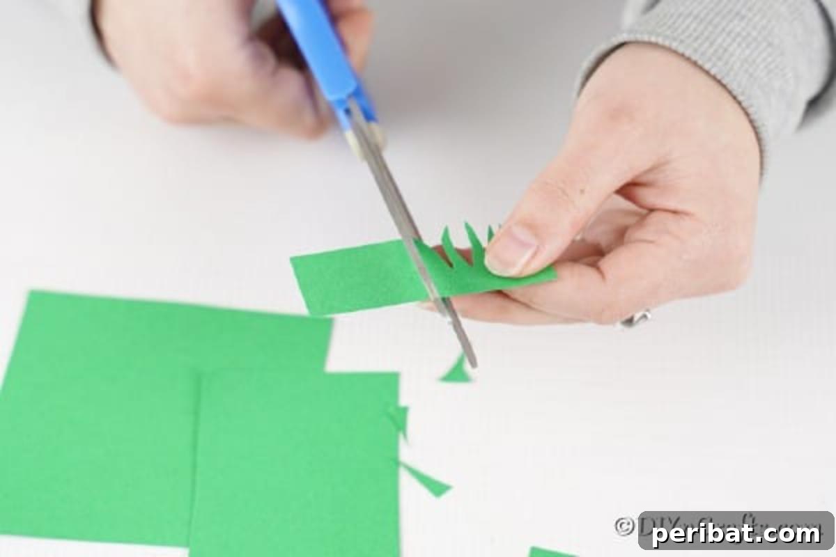 DIY Easter Treat Pouch Video Guide 18 A hand cutting fringe into a strip of green paper to create a grass effect
