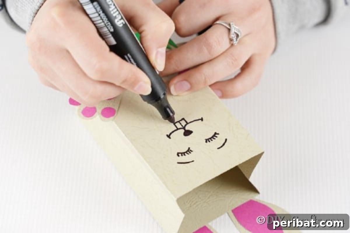 DIY Easter Treat Pouch Video Guide 20 A hand drawing a bunny face onto the paper bag with a black marker
