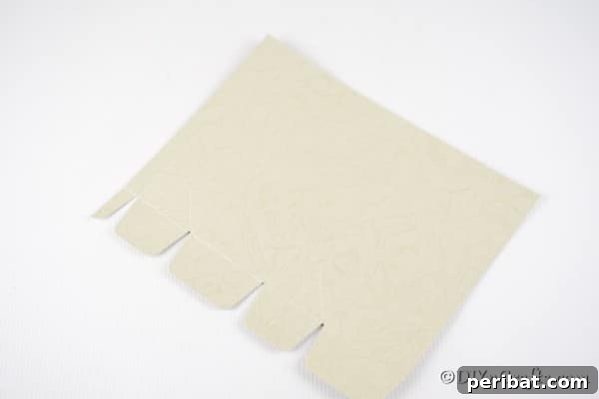 DIY Easter Treat Pouch Video Guide 9 White paper with four distinct notches cut along one edge, prepared for folding
