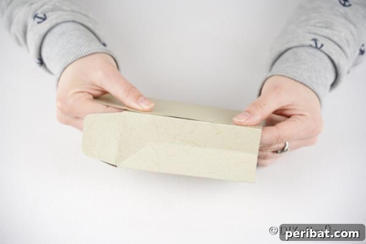 DIY Easter Treat Pouch Video Guide 10 Hands folding a piece of paper to form the base of a bag, with bottom flaps beginning to overlap