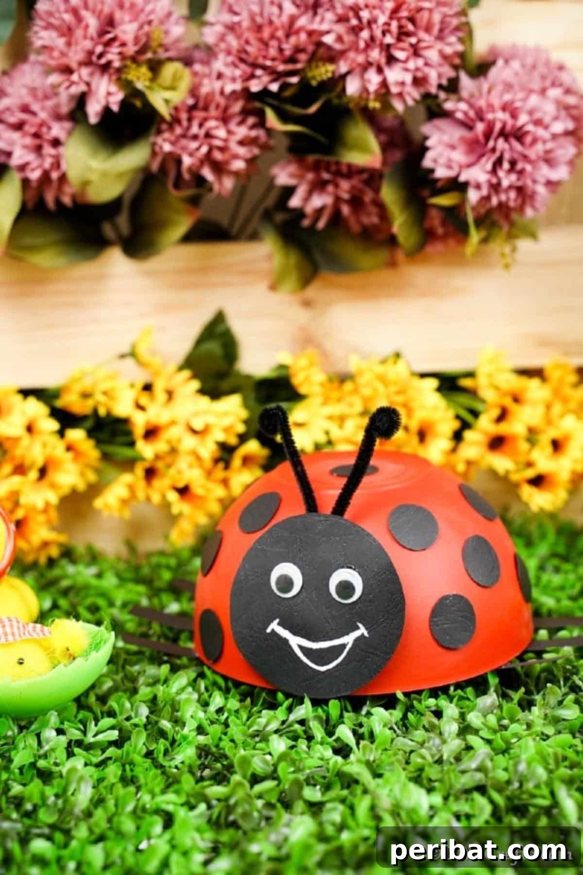 Repurposed Ladybug Bowl Art 5 A vibrant ladybug craft made from an upcycled bowl, positioned in front of charming pink and yellow flowers, perfect for garden decoration.