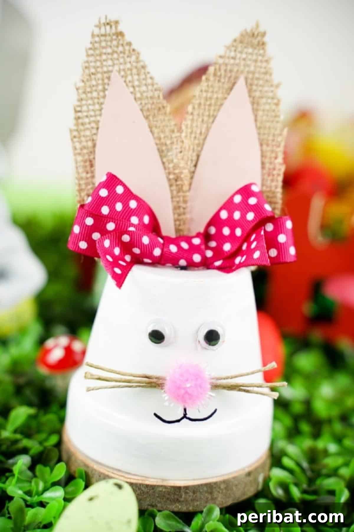Charming Repurposed Planter Bunnies for Easter 4 Side view of an upcycled flower pot Easter bunny with a pink bow, sitting on green grass.