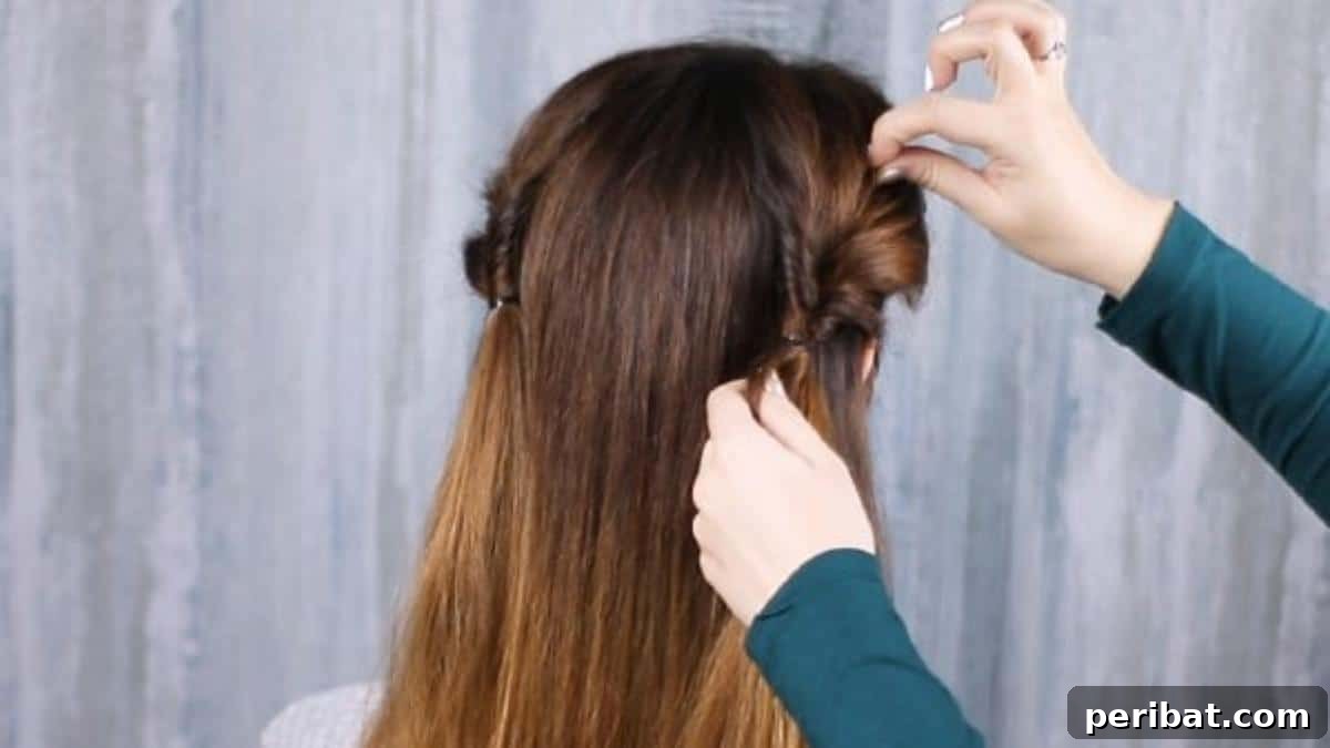Rose-Kissed Low Bun Updo 11 The process of pulling hair through the ponytail on the second side, mirroring the first twisted section.