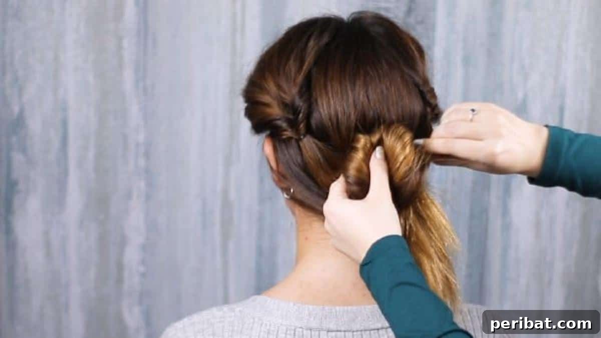 Rose-Kissed Low Bun Updo 17 Folding the voluminous section of hair upwards towards the scalp, beginning to form the core of the low bun.