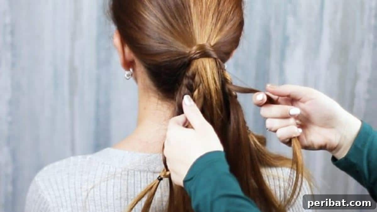 Hands beginning to braid the integrated sections together, forming the core of the fishtail