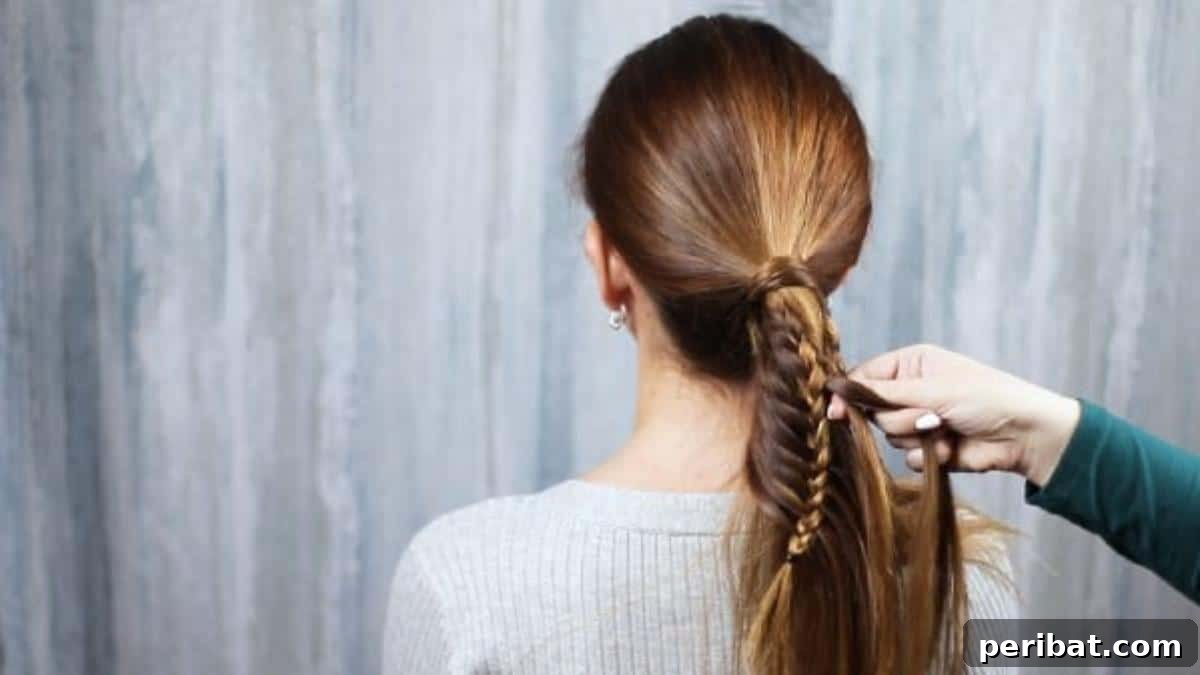 Brunette hair being intricately braided, showing the progression of the fishtail pattern