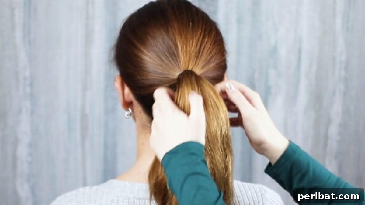 Hands pulling hair back into a mid-level ponytail, ready for braiding