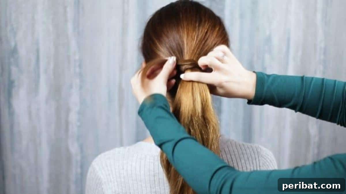 A small section of hair being wrapped around the ponytail holder to hide it